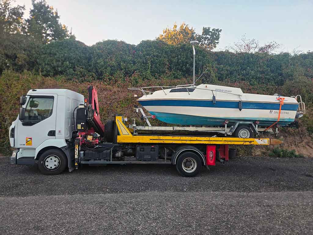 Bateau de plaisance hors d'usage et sa remorque chargés sur le camion plateau de Ferrailleur Lyon